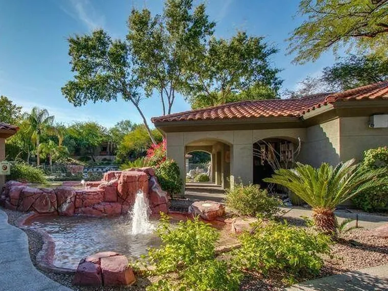 Stucco condominium entry with a red tile roof, arched walkway and a desert garden fountain at 5751 N Kolb Rd Unit 37203, Tucson, Arizona
